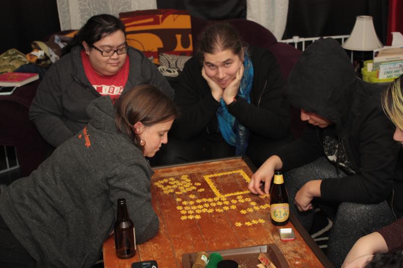 Group of people doing a jigsaw puzzle, Jamila Ruya Khan looking at the camera